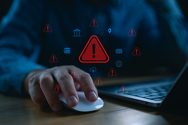 Hand on a computer mouse with red alert triangles in the foreground